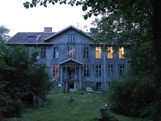 Ett stort grått hus. Vrångsholmen som ligger utanför Tanumshede mot Strömstad.