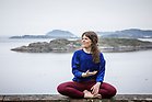 Josefin Andersson sittande i yogapostion med skärgården i bakgrunden